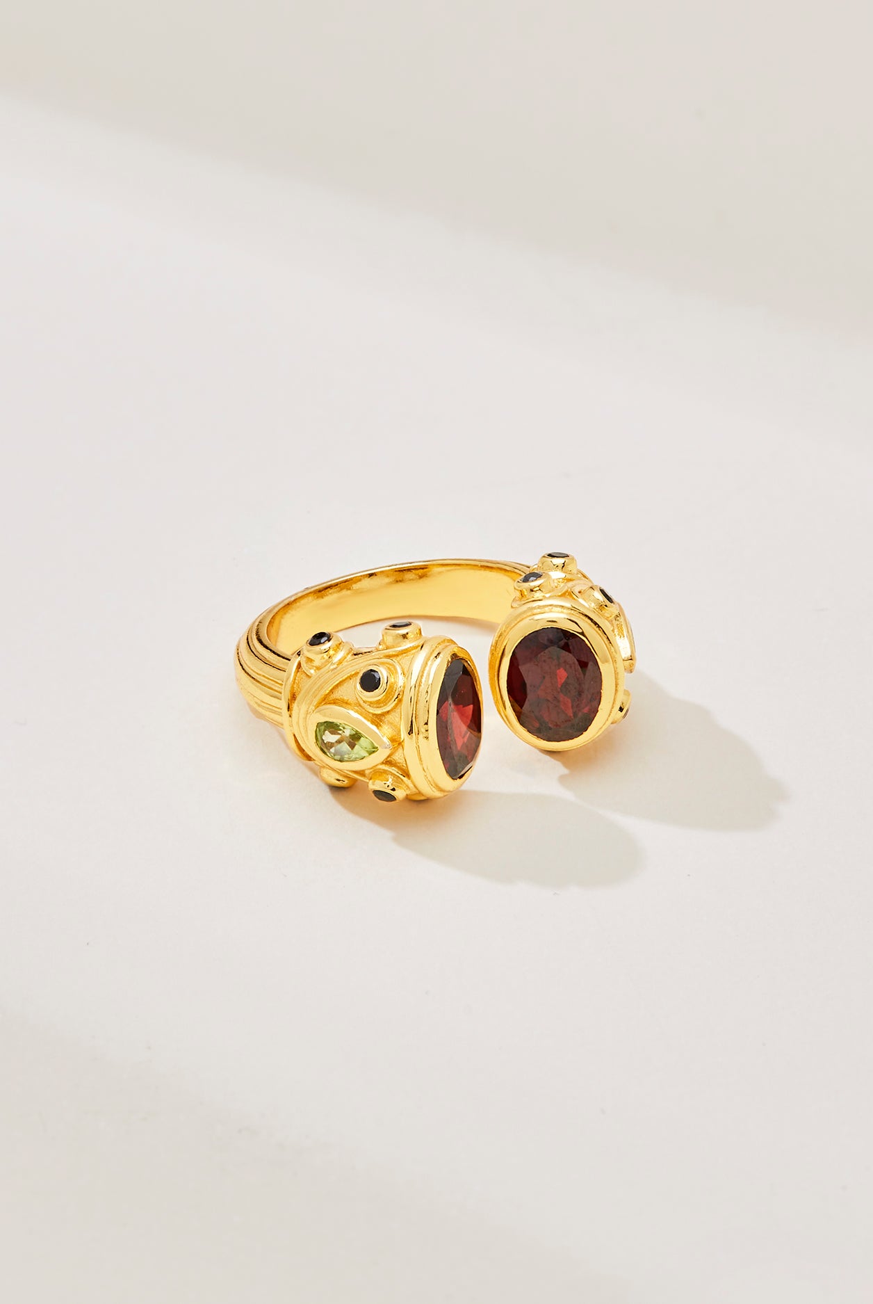 A sterling silver and gold plated petite Sheida ring, set with garnet, peridot and black onyx, displayed against a white background.