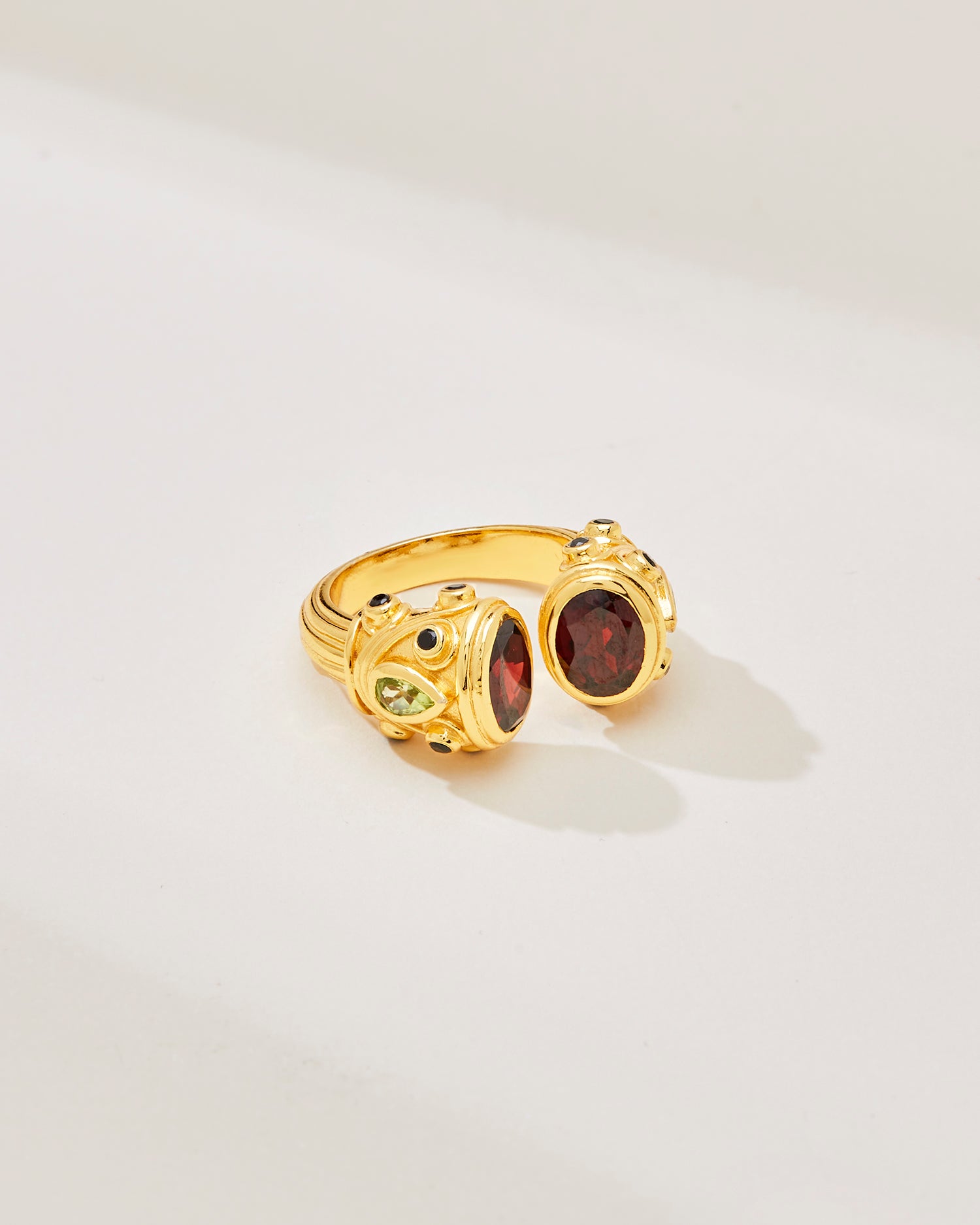 A sterling silver and gold plated petite Sheida ring, set with garnet, peridot and black onyx, displayed against a white background.