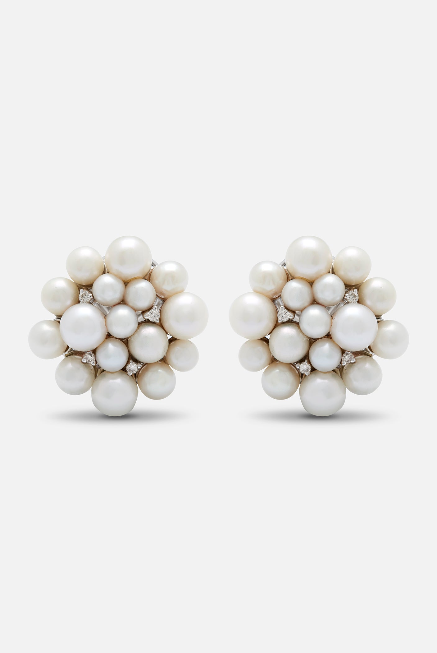 A pair of 18K white gold stud earrings with a central pearl cluster and smaller pearl accents.