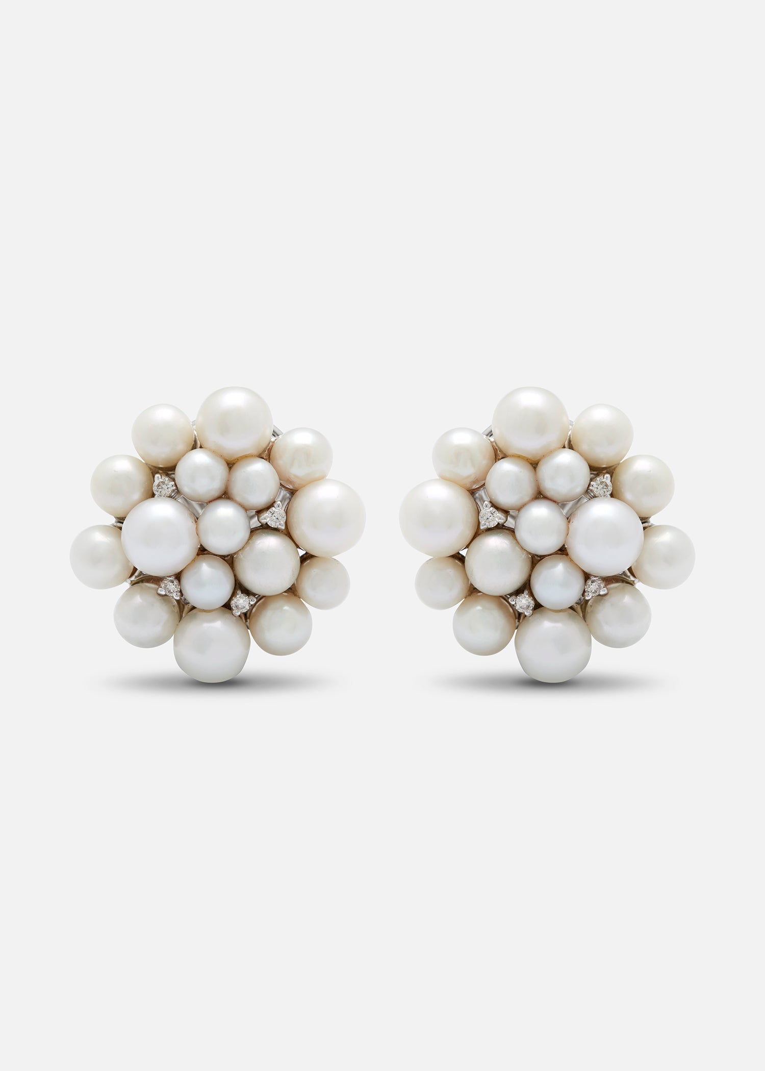 A pair of 18K white gold stud earrings with a central pearl cluster and smaller pearl accents.