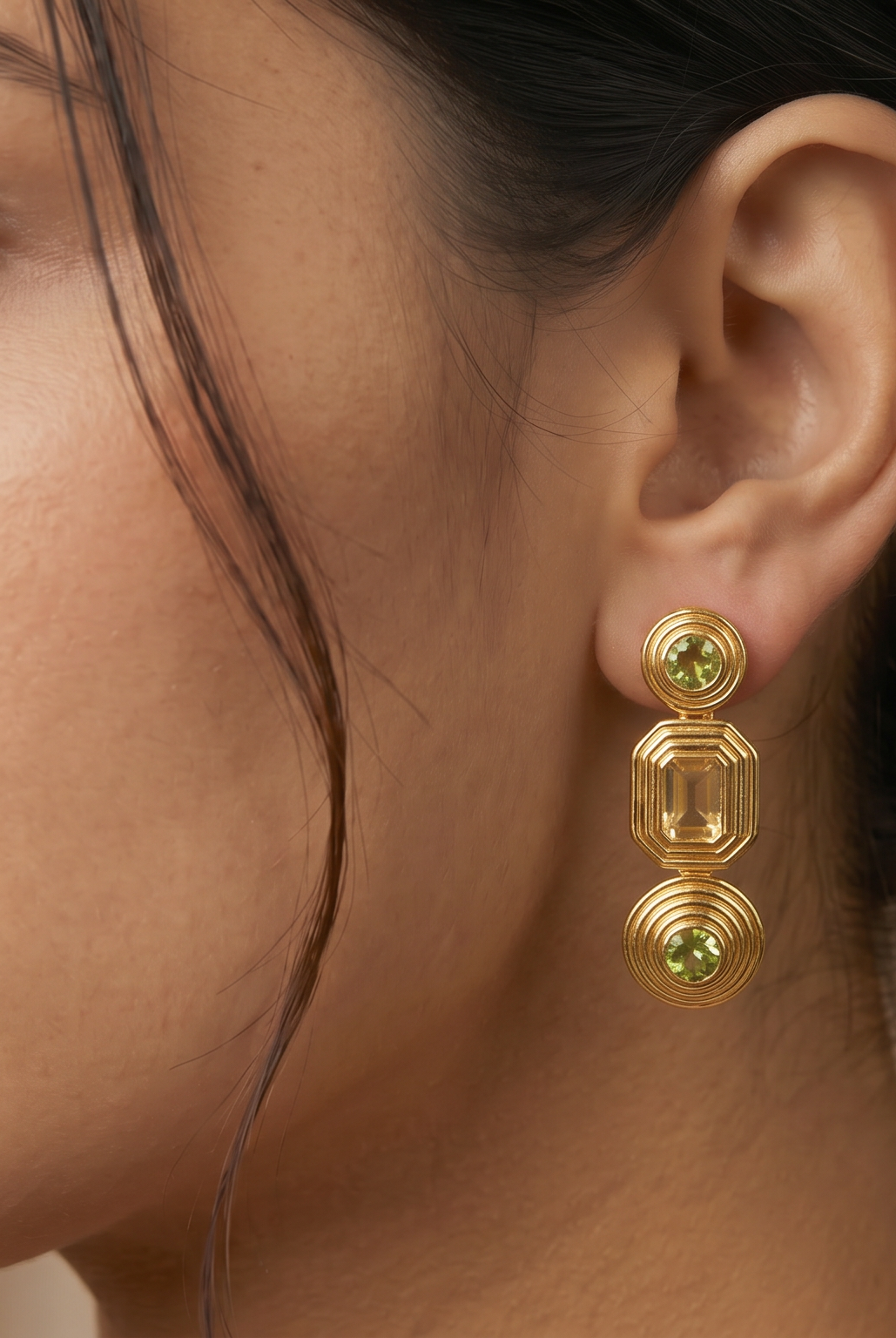 AI Image: Woman wearing gold cascade earrings with green and yellow gemstones a neutral background