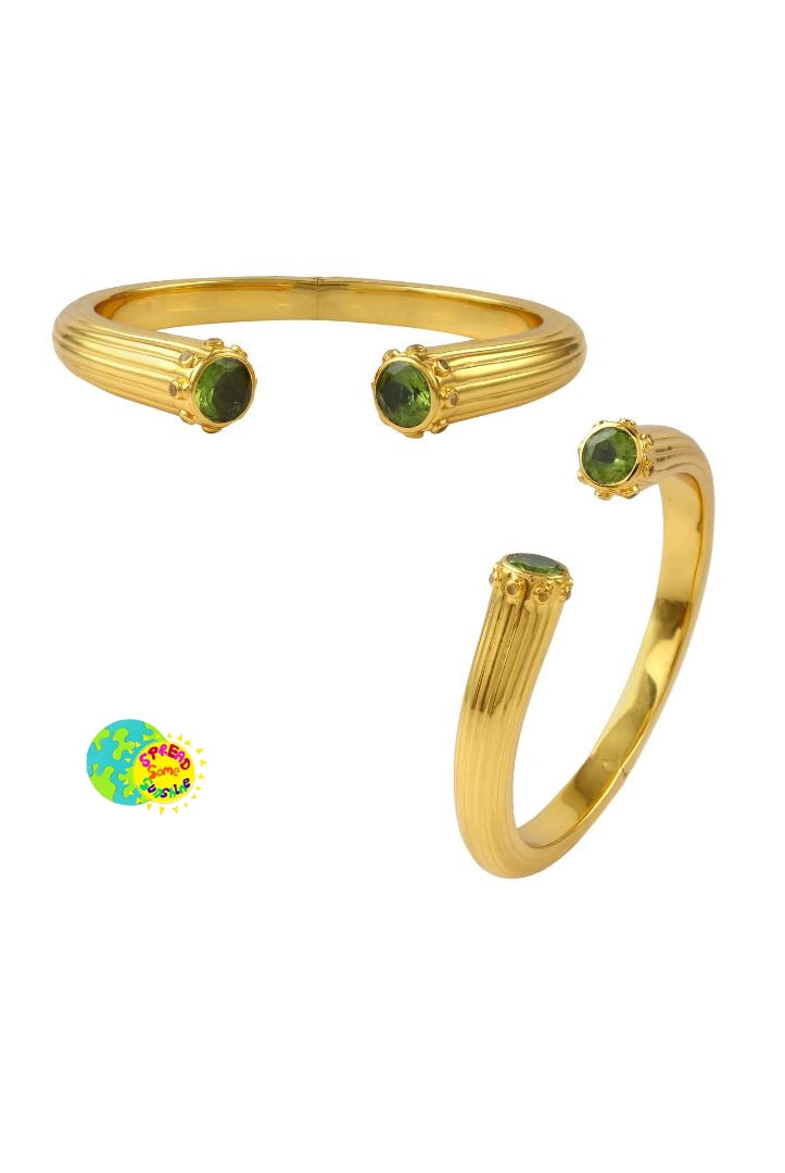 Gold cuff bangle with green and yellow gemstones on a white background