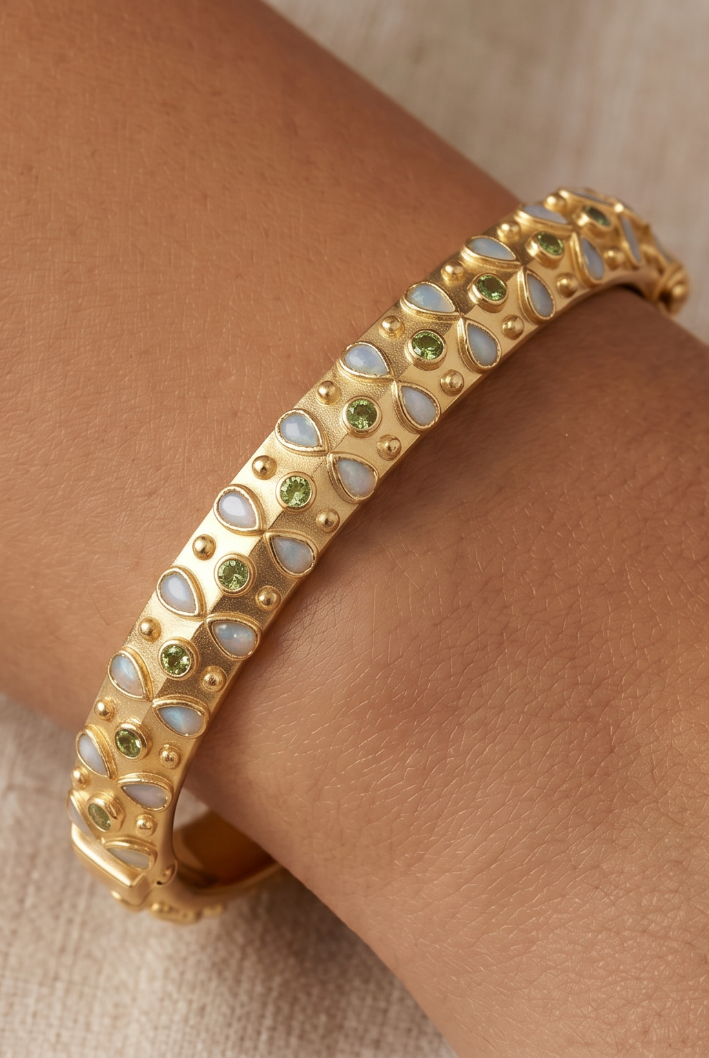 AI Image : Gold bangle with embedded light blue and green stones on a wrist against a neutral background