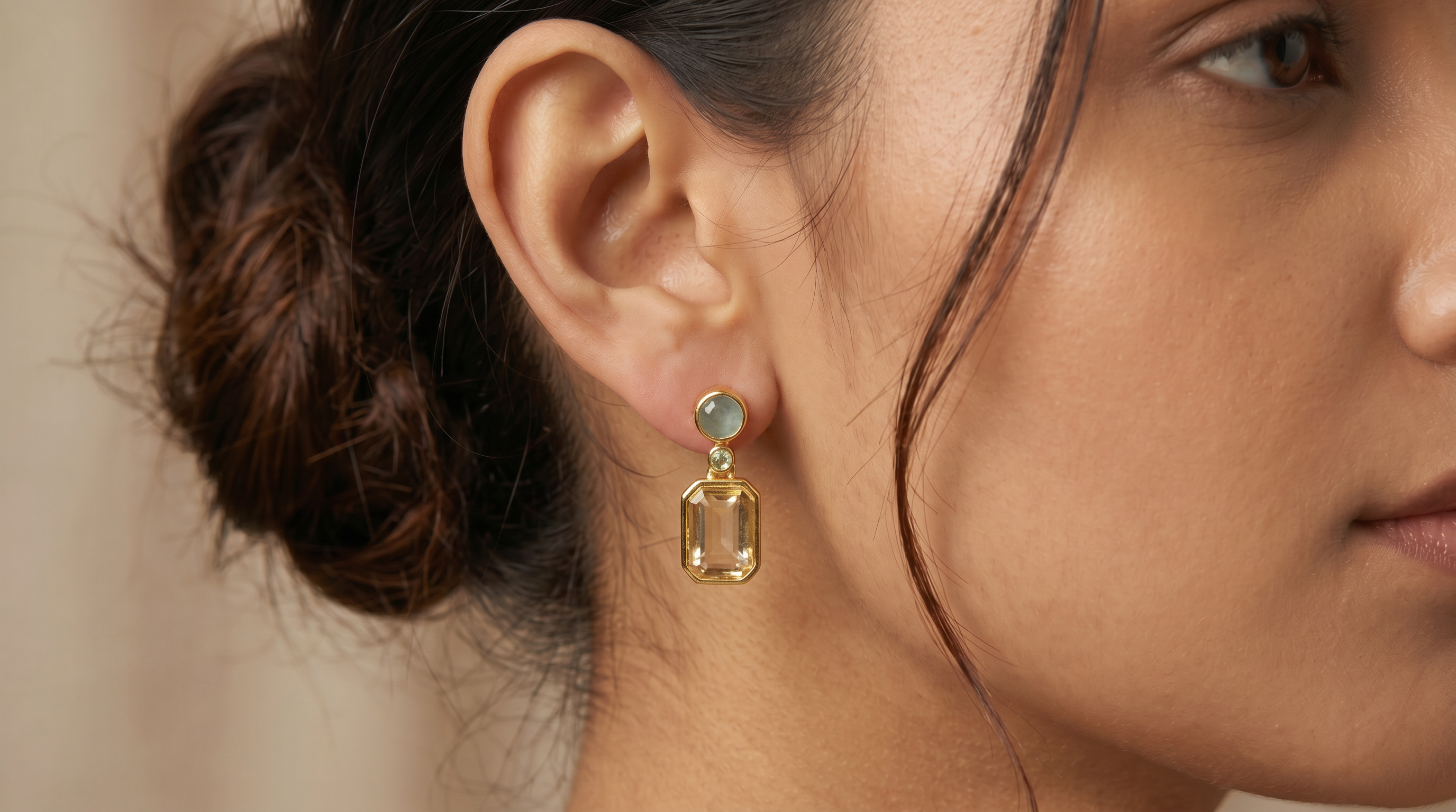 AI Image: Close-up of a woman wearing gold round and rectangular drop earrings with light blue and green gemstones against a neutral  background