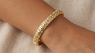AI Image : Gold bangle with embedded light blue and green stones on a wrist against a neutral background